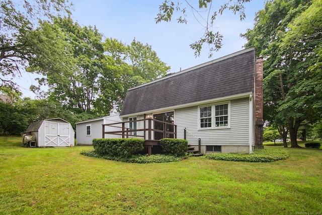 rear view of house featuring a yard, a deck, and a storage unit