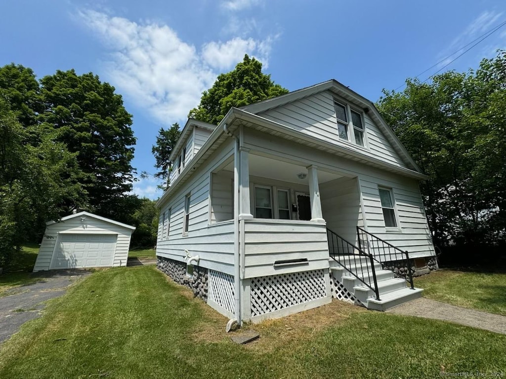 bungalow-style house with a front yard, a garage, and an outdoor structure