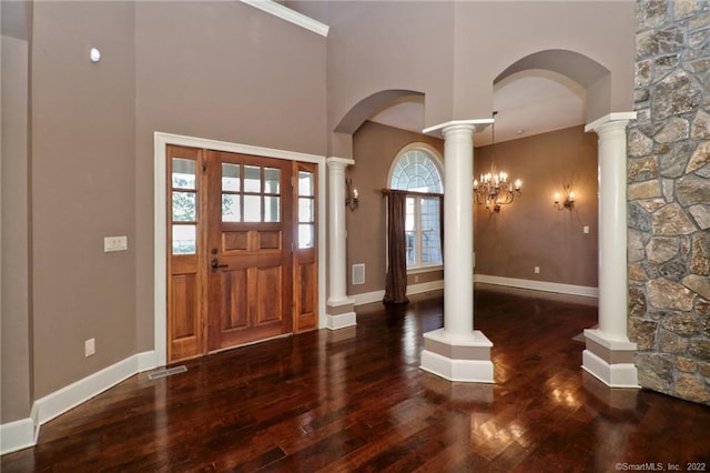 foyer entrance featuring a chandelier, dark hardwood / wood-style flooring, ornate columns, and a healthy amount of sunlight