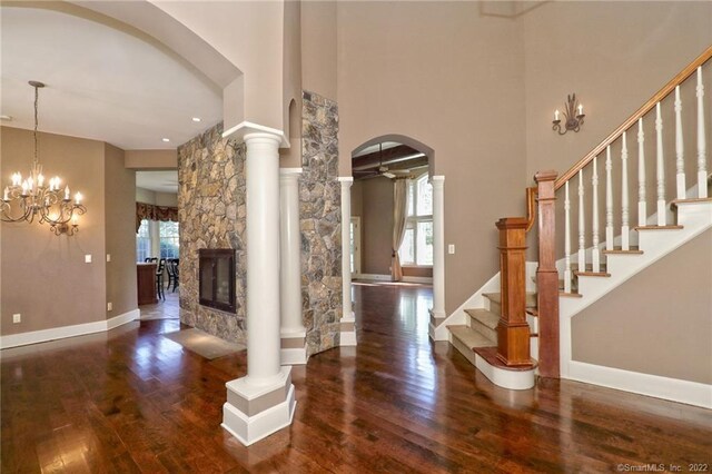 entrance foyer with decorative columns, a fireplace, dark hardwood / wood-style flooring, and a chandelier