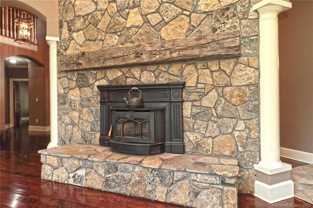 details with decorative columns, hardwood / wood-style floors, and a wood stove