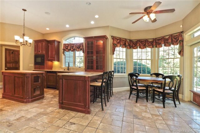 kitchen featuring black microwave, decorative light fixtures, a center island, and light tile patterned floors