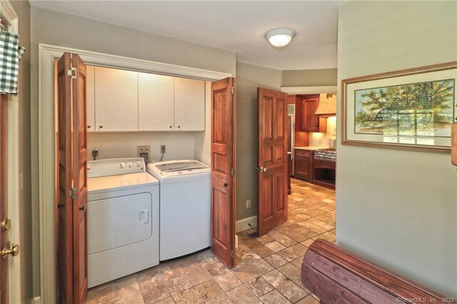 laundry room with cabinets, washer and clothes dryer, and light tile patterned floors