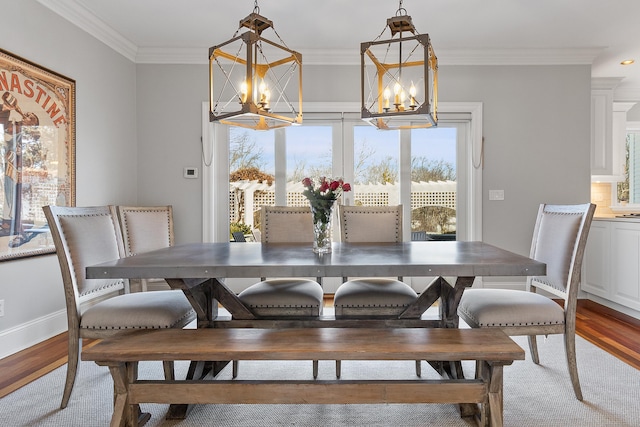dining space with a chandelier, baseboards, wood finished floors, and crown molding