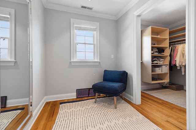 sitting room featuring wood finished floors, visible vents, ornamental molding, and baseboards