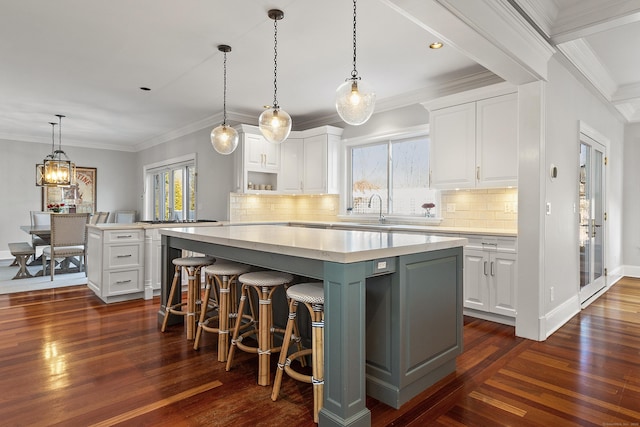 kitchen featuring decorative backsplash, light countertops, a kitchen island, white cabinets, and dark wood-style flooring