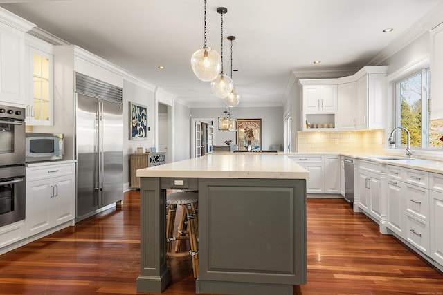 kitchen with recessed lighting, a sink, a kitchen island, white cabinets, and appliances with stainless steel finishes