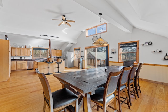 dining space with light wood-type flooring, sink, lofted ceiling with beams, and ceiling fan