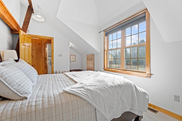 bedroom featuring vaulted ceiling with beams and hardwood / wood-style floors