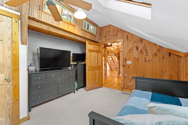 bedroom featuring light hardwood / wood-style floors, lofted ceiling with skylight, and wood walls