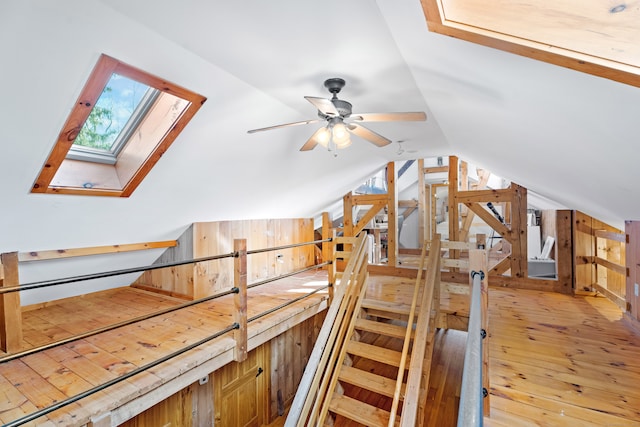 bonus room with ceiling fan, light hardwood / wood-style flooring, and vaulted ceiling with skylight