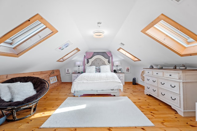 bedroom featuring lofted ceiling with skylight and light hardwood / wood-style flooring