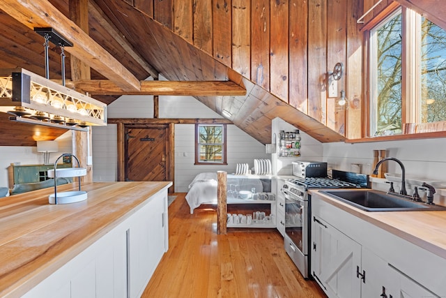 kitchen featuring wood counters, white cabinetry, gas stove, light wood-type flooring, and sink