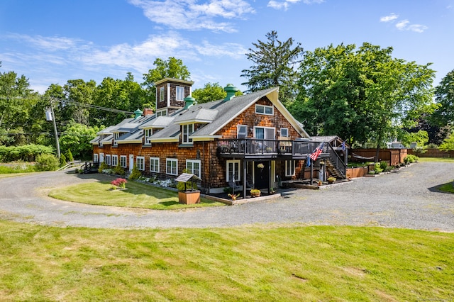 back of property featuring a deck and a lawn