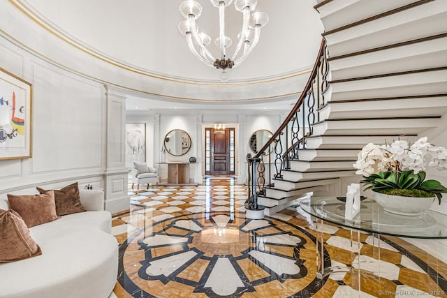 entryway with ornate columns, crown molding, and an inviting chandelier