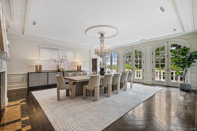 dining space with crown molding, french doors, a high end fireplace, and a chandelier