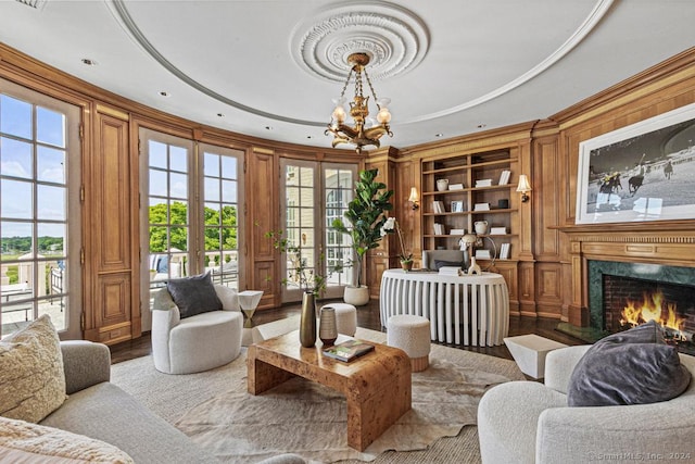 living area with a high end fireplace, an inviting chandelier, french doors, light hardwood / wood-style flooring, and built in shelves