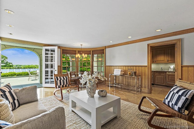 living room with a notable chandelier, crown molding, and french doors