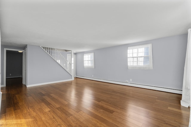 unfurnished living room with hardwood / wood-style floors and a baseboard heating unit