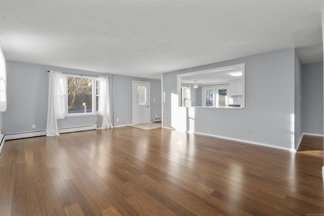 unfurnished living room with hardwood / wood-style floors and a baseboard heating unit