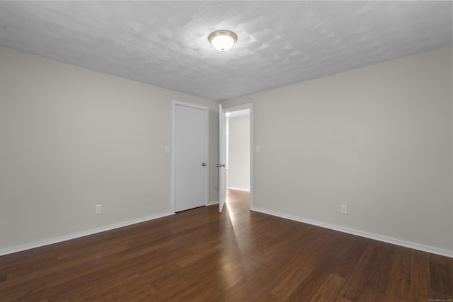 spare room featuring a textured ceiling and dark hardwood / wood-style flooring