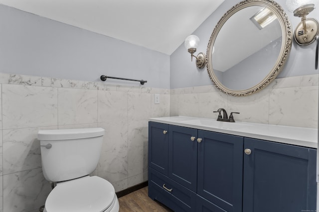 bathroom with vanity, hardwood / wood-style flooring, tile walls, toilet, and lofted ceiling