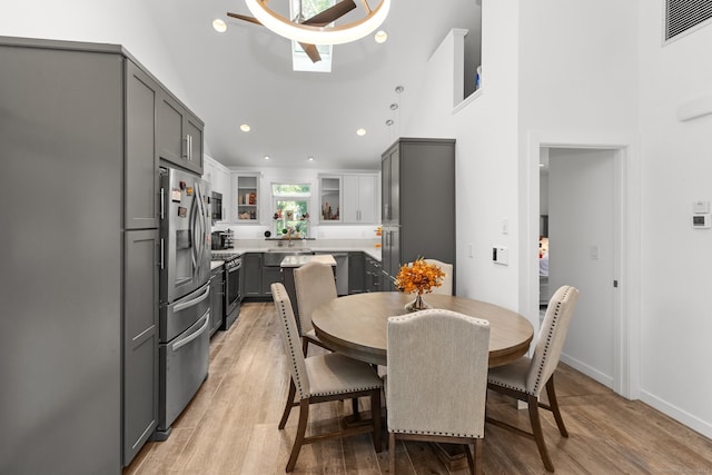 dining room featuring a skylight, light hardwood / wood-style flooring, and a high ceiling