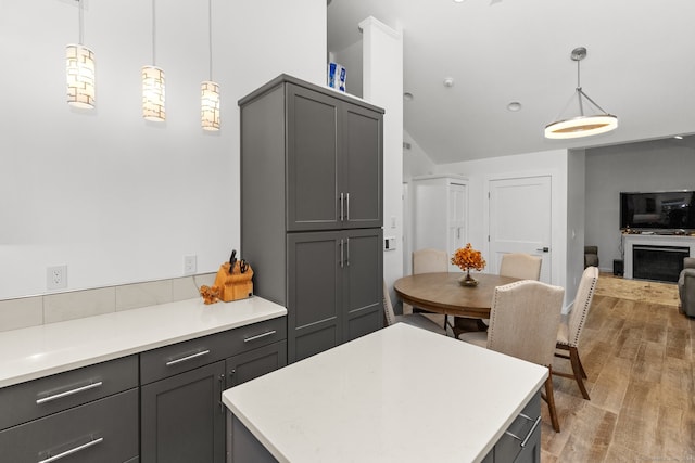 kitchen with hanging light fixtures, light hardwood / wood-style floors, vaulted ceiling, gray cabinets, and a kitchen island