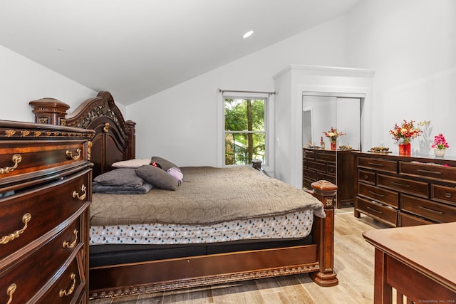 bedroom featuring light wood-type flooring, a closet, and lofted ceiling