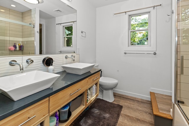 bathroom featuring backsplash, wood-type flooring, toilet, a shower with door, and vanity