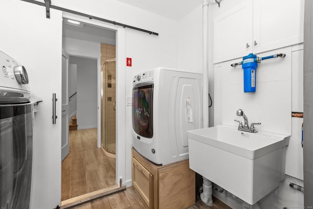 clothes washing area with hardwood / wood-style floors, a barn door, sink, and washer / clothes dryer