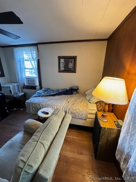 bedroom with cooling unit, dark hardwood / wood-style floors, and ornamental molding