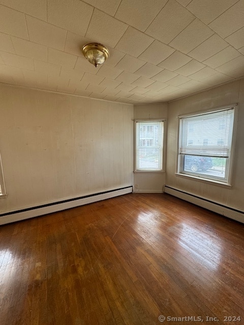 spare room with hardwood / wood-style flooring and a baseboard heating unit