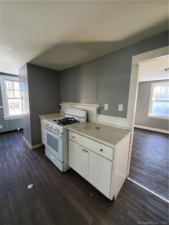 kitchen with dark wood-type flooring, white cabinetry, and white gas range