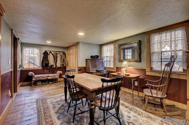 dining area with a textured ceiling and light hardwood / wood-style flooring