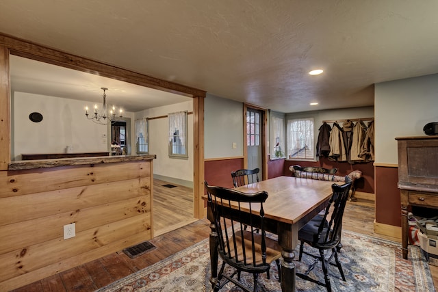 dining room featuring a textured ceiling, a notable chandelier, and light wood-type flooring