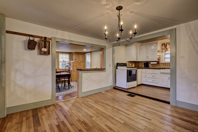 kitchen with white cabinetry, light hardwood / wood-style flooring, white range with electric cooktop, plenty of natural light, and decorative light fixtures