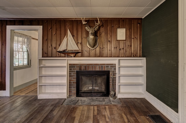 interior details featuring hardwood / wood-style floors, a brick fireplace, and wood walls