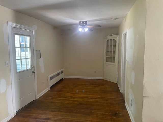 unfurnished dining area featuring ceiling fan, dark wood-type flooring, and radiator