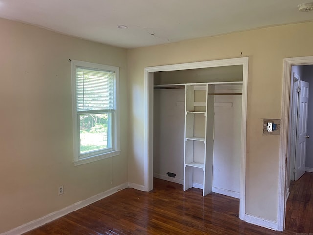 unfurnished bedroom with dark hardwood / wood-style flooring and a closet