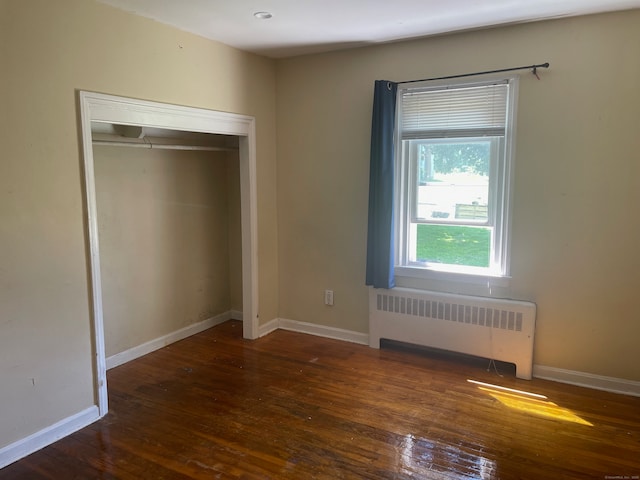 unfurnished bedroom featuring dark hardwood / wood-style floors, a closet, and radiator