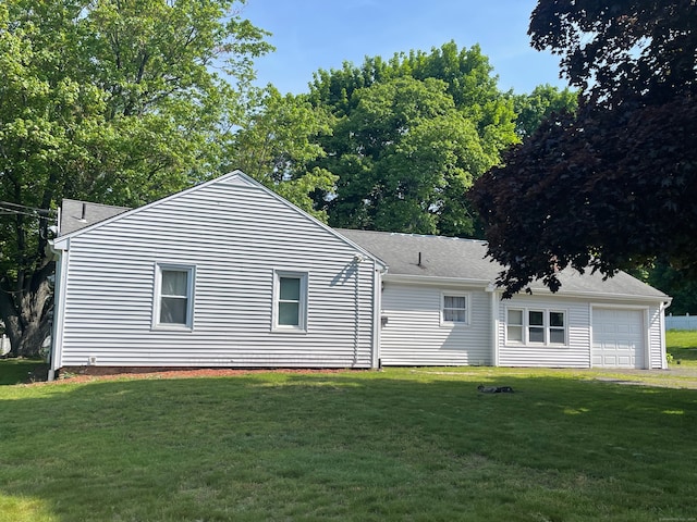 rear view of house with a garage and a lawn