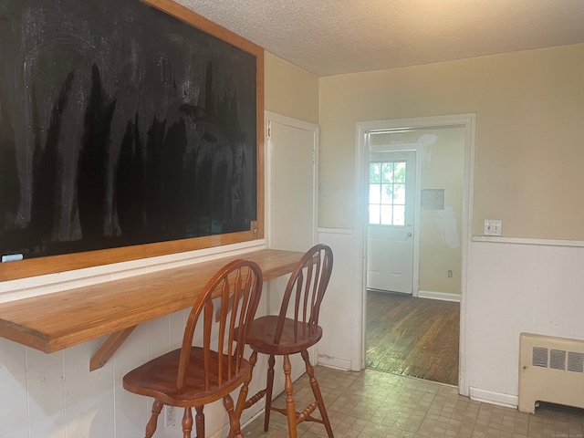 dining area with tile flooring, a textured ceiling, and radiator