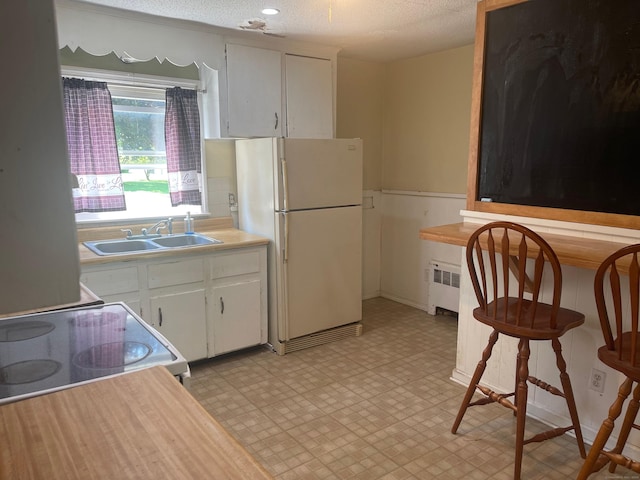 kitchen featuring sink, white appliances, a textured ceiling, and white cabinets