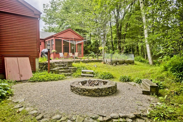 view of yard featuring a sunroom, an outdoor fire pit, and a patio