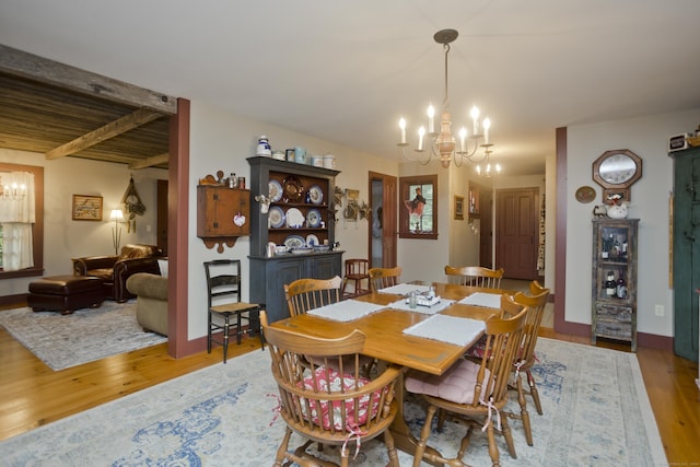 dining room featuring light hardwood / wood-style flooring, beamed ceiling, and a notable chandelier