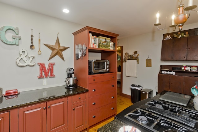 kitchen with light hardwood / wood-style floors, dark stone countertops, and gas cooktop