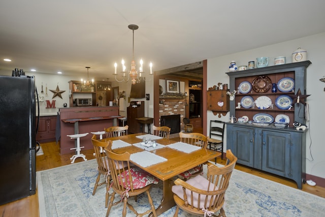 dining space featuring a fireplace, light hardwood / wood-style floors, and a notable chandelier