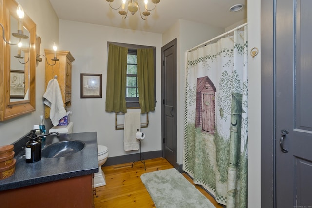 bathroom with hardwood / wood-style floors, vanity, a chandelier, and toilet