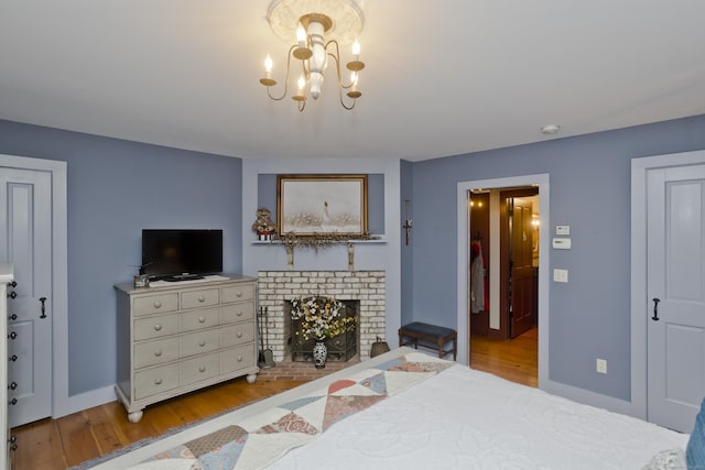 bedroom featuring a fireplace, a chandelier, and light hardwood / wood-style floors